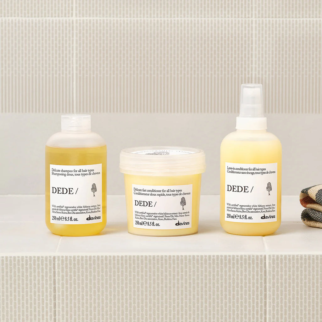 Dede Leave in Conditioner i en gulvit sprayflaska tillsammans med matchande miljövänliga hårvårdsprodukter från Davines på en hylla i ett badrum.