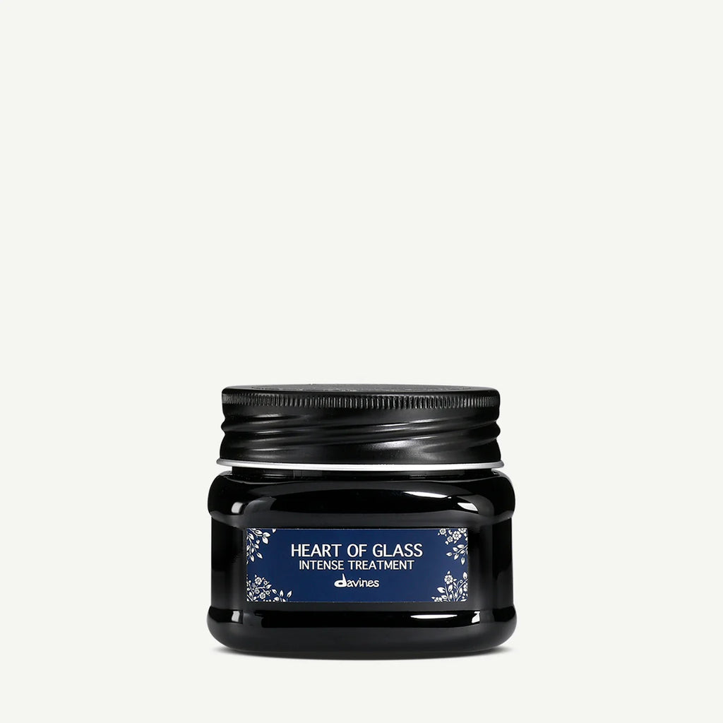 Svart burk med Heart of Glass Intense Treatment, en hårinpackning från Davines med blå etikett och vit text för intensiv hårvård.