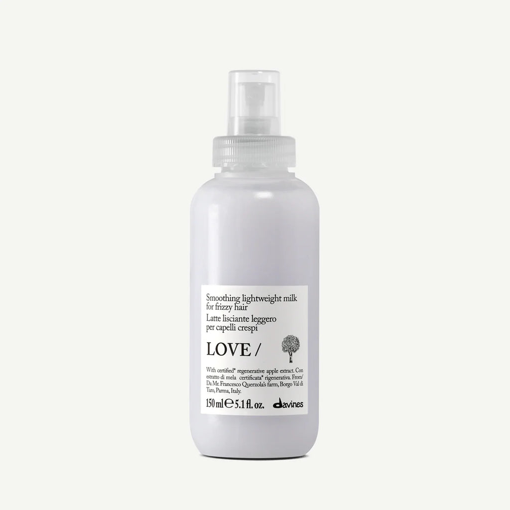 Flaska med Love Smoothing Lightweight Milk, en lättviktig stylingprodukt för att mjukgöra och kontrollera hår, med pumpflaska och vit etikett.