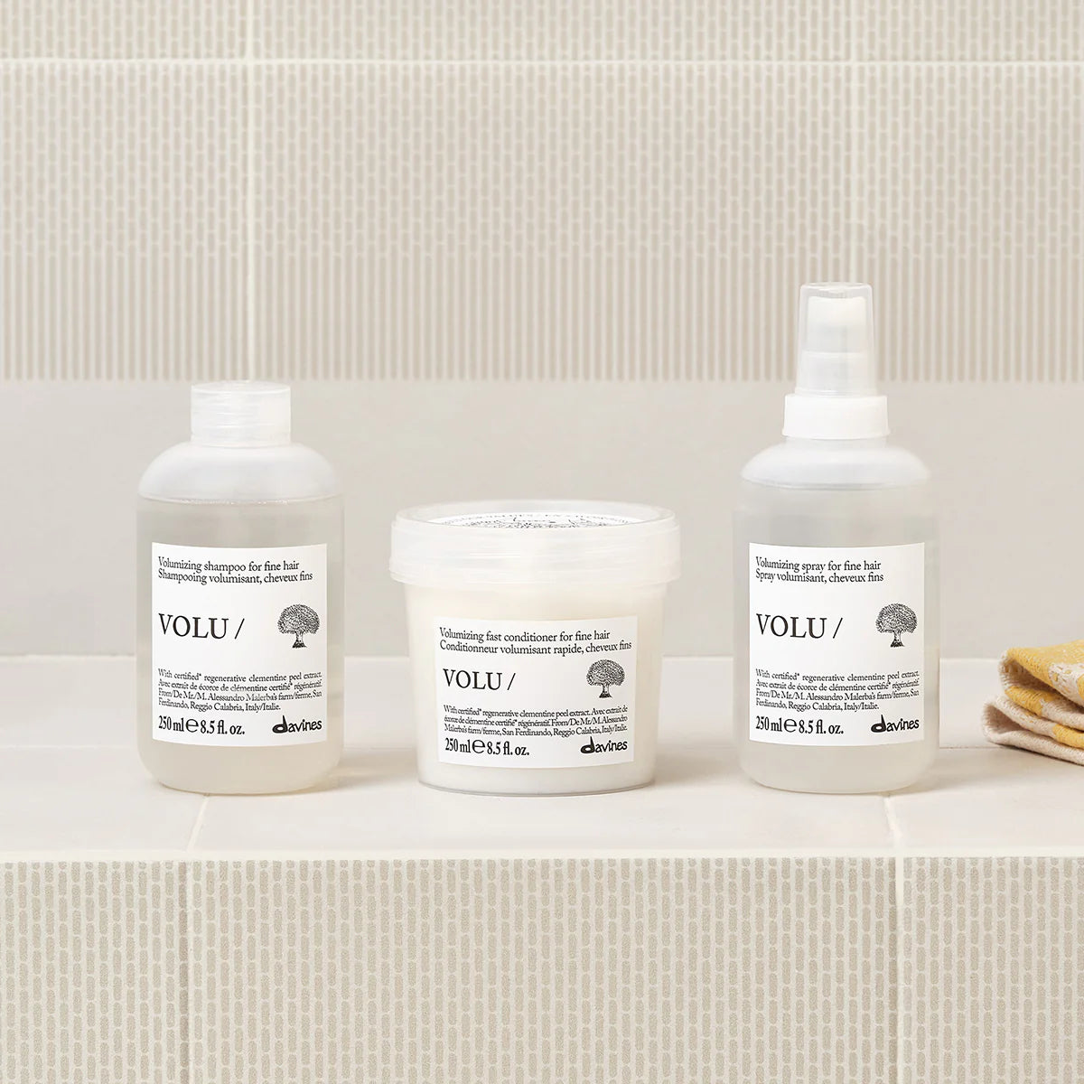 Volu Volumizing Shampoo tillsammans med matchande balsam och spray i enkel, stilren förpackning på bänk i badrum med mjuka beige toner.