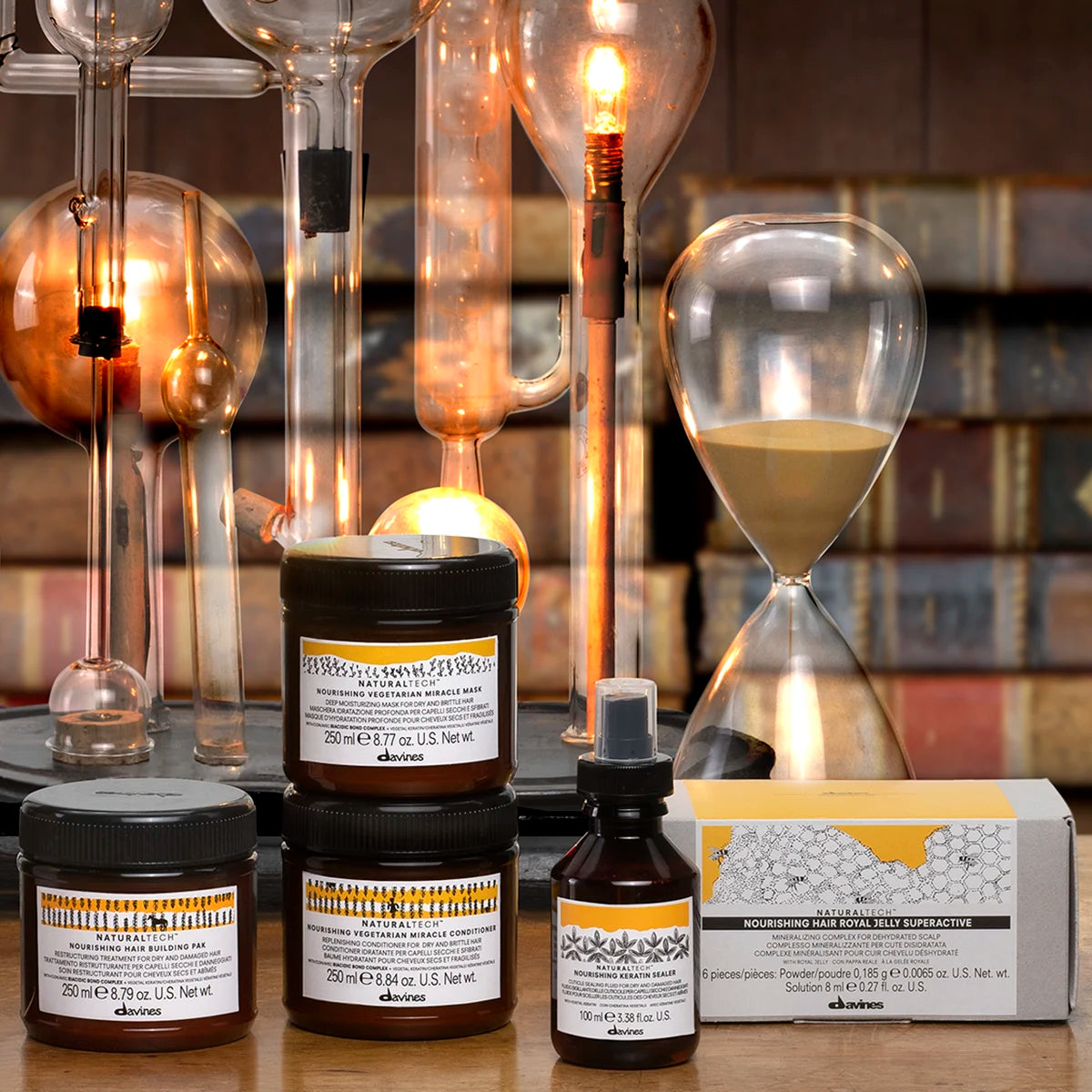Naturlig hårvårdsserie med Naturaltech Nourishing Keratin Sealer, inklusive balsam och hårinpackning, presenterad med timglas och varmt ljus för en inbjudande atmosfär.